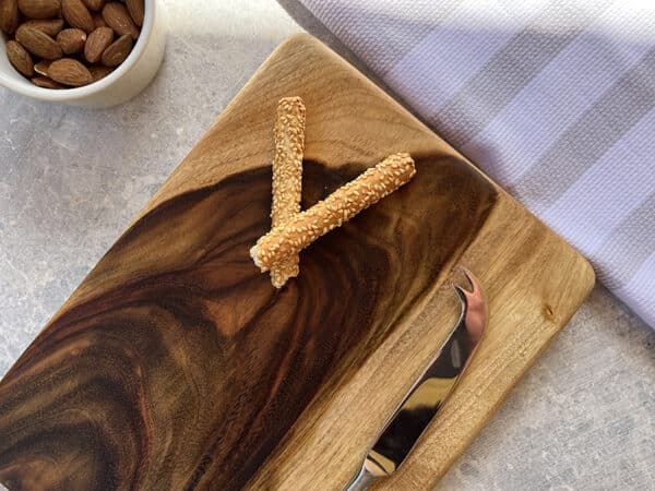 Wooden cutting board with a knife and a bowl of almonds