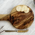 Wooden cutting board with crackers and a knife