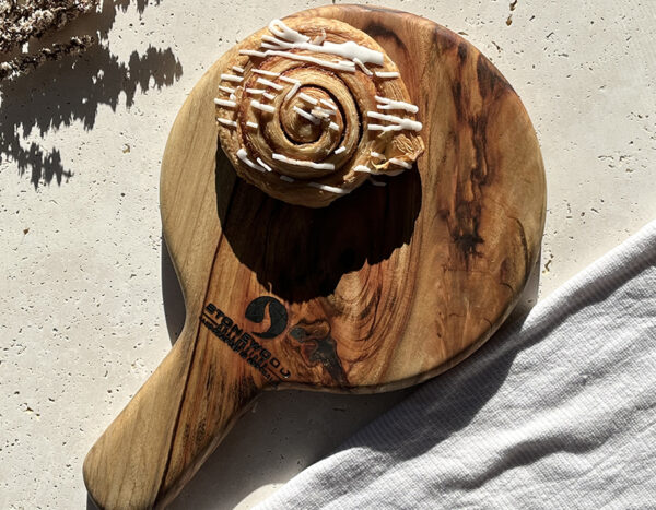 A cinnamon roll on a wooden cutting board