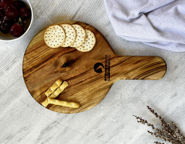 A wooden board with crackers and a bowl of grapes