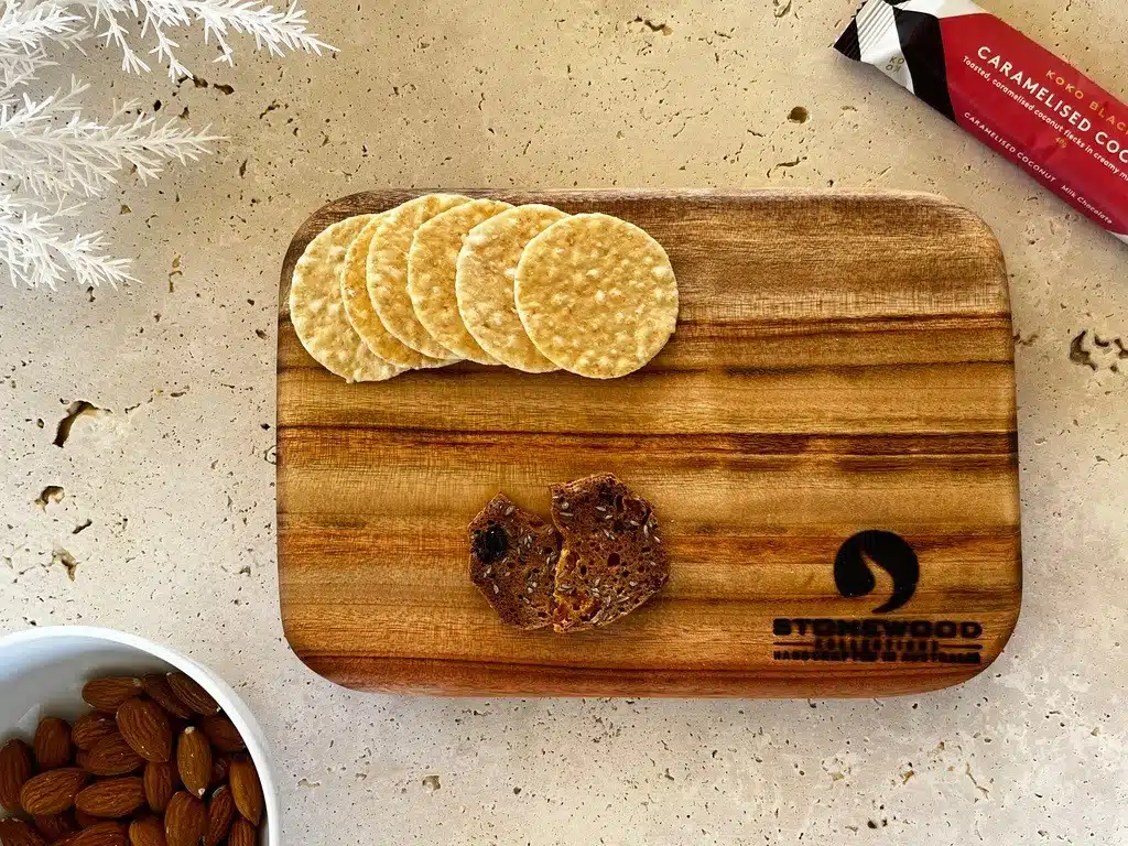 Wooden cutting board with crackers and a bowl of almonds
